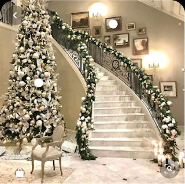 A staircase with white Christmas decorations next to a Christmas tree