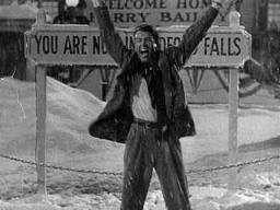 A man cheering infront of signs outside with snow surrounding him