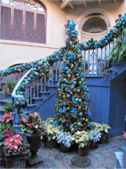 A christmas tree inside with blue decorations next to a blue staircase