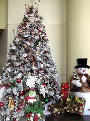 A Christmas tree with artifical snow and decorations next to festive decorations