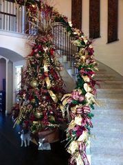 A decorated christmas tree next to a staircase with garland