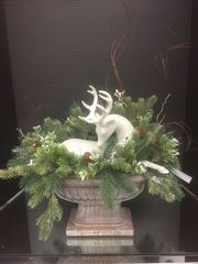 A white reindeer decoration inside a vase with greenery